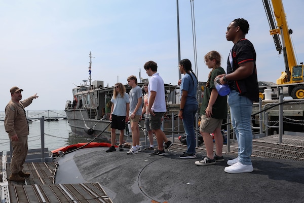 College students listen to a Submariner explain the different functions of the vessel during a tour of USS Oregon.