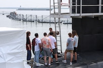 College students listen to a Submariner explain the different functions of the vessel during a tour of USS Oregon.