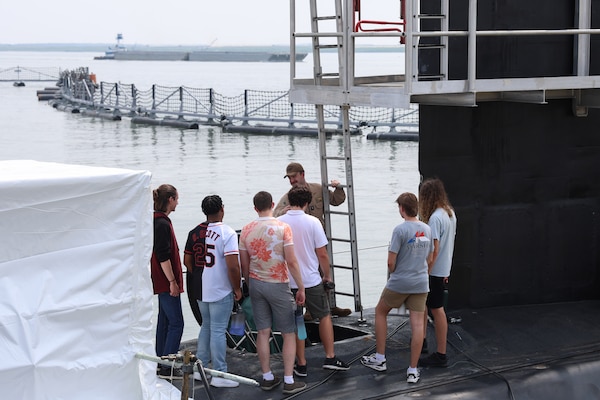 College students listen to a Submariner explain the different functions of the vessel during a tour of USS Oregon.