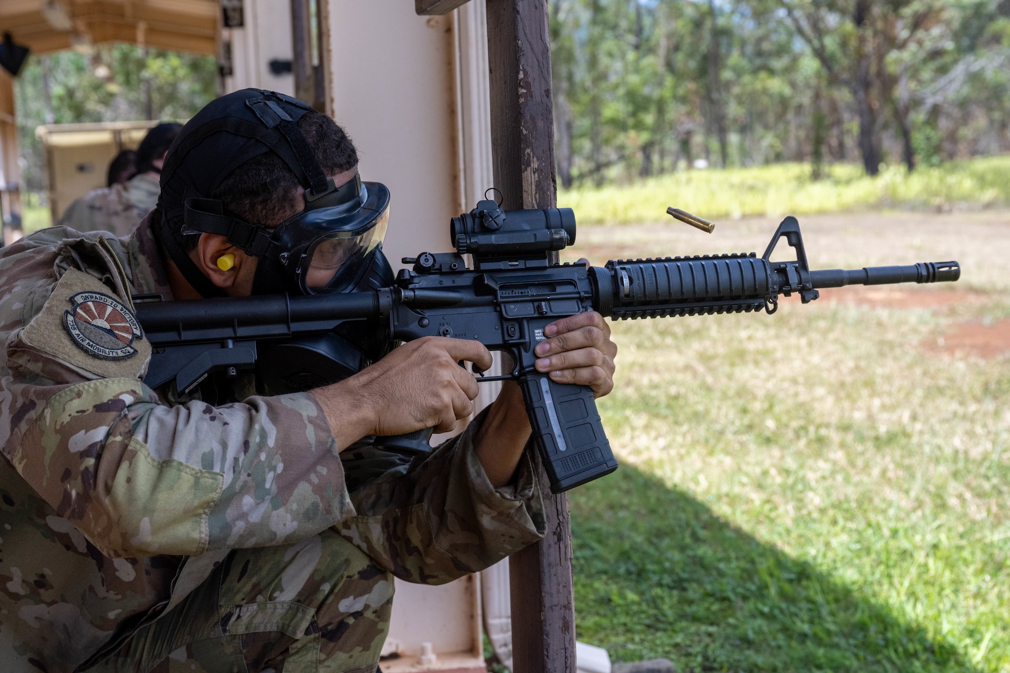 A U.S. Air Force Airmen fires an M4 carbine rifle at practice targets while wearing a gas mask during combat arms training and maintenance.