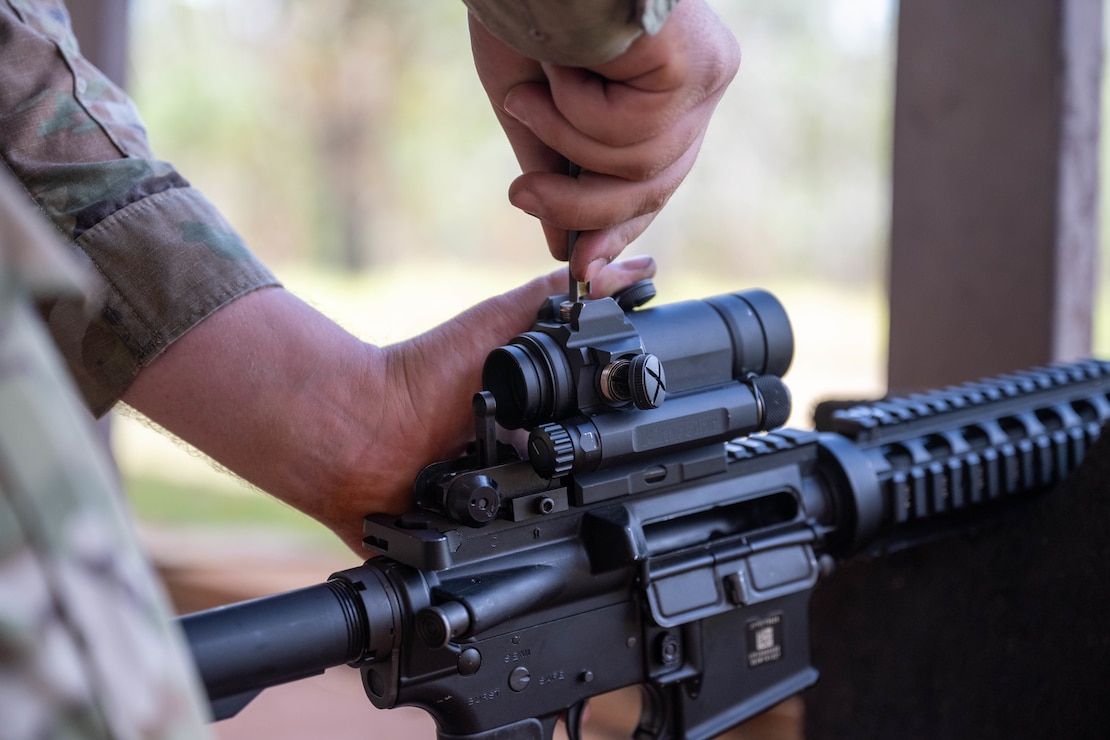 A U.S. Air Force Airmen adjusts the red dot sight on his M4 carbine rifle during combat arms training and maintenance.