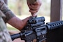 A U.S. Air Force Airmen adjusts the red dot sight on his M4 carbine rifle during combat arms training and maintenance.
