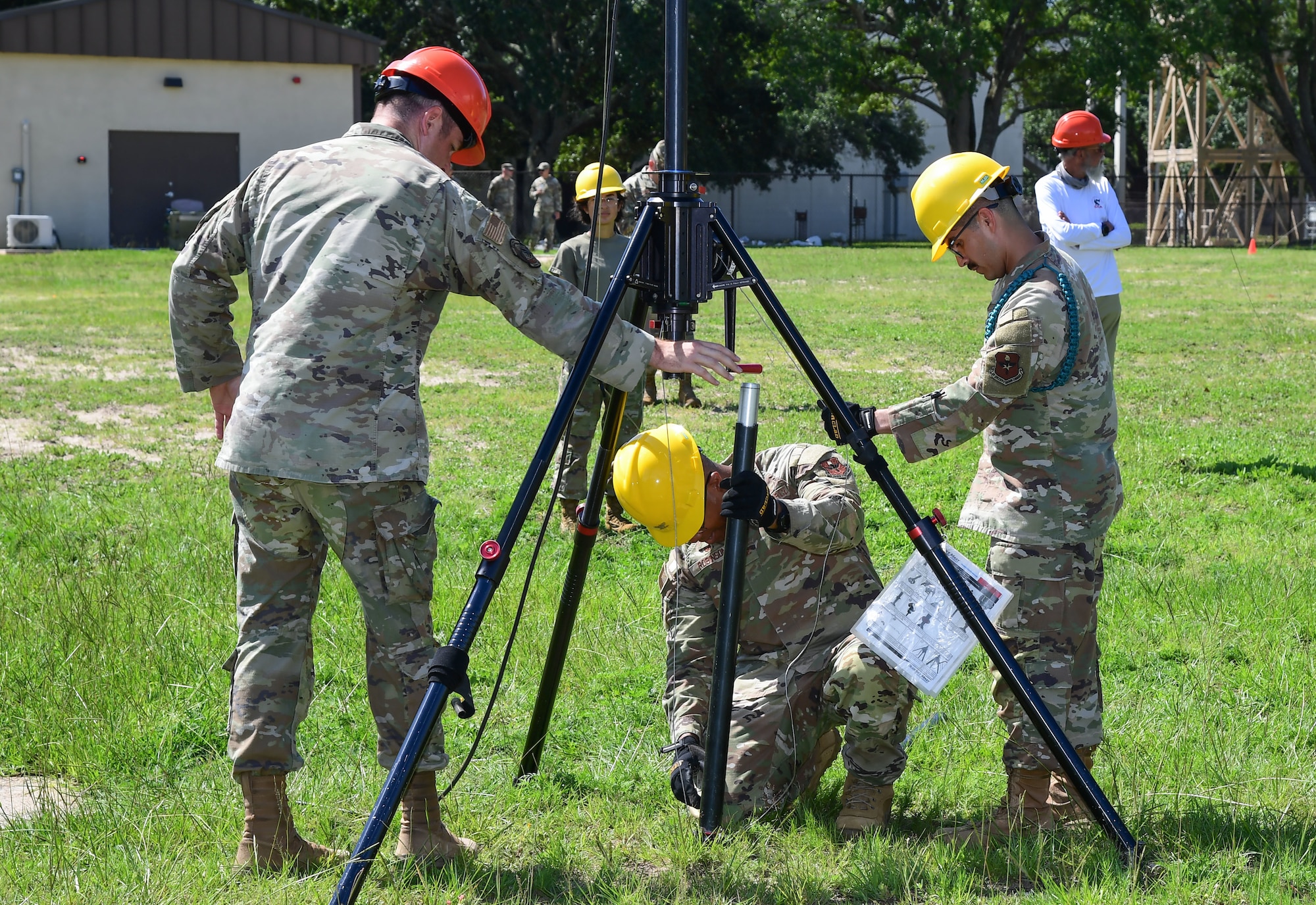 Men in military uniform stand near an antennae.