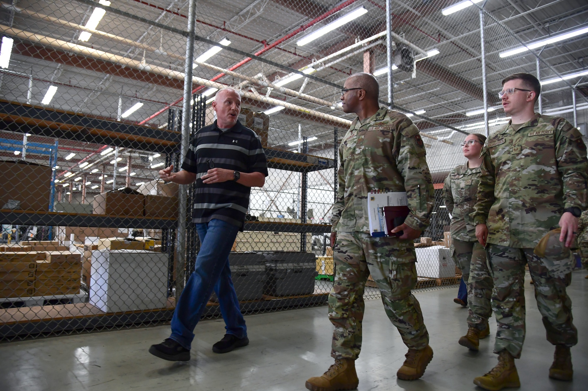 Men in military uniforms walk inside a warehouse.