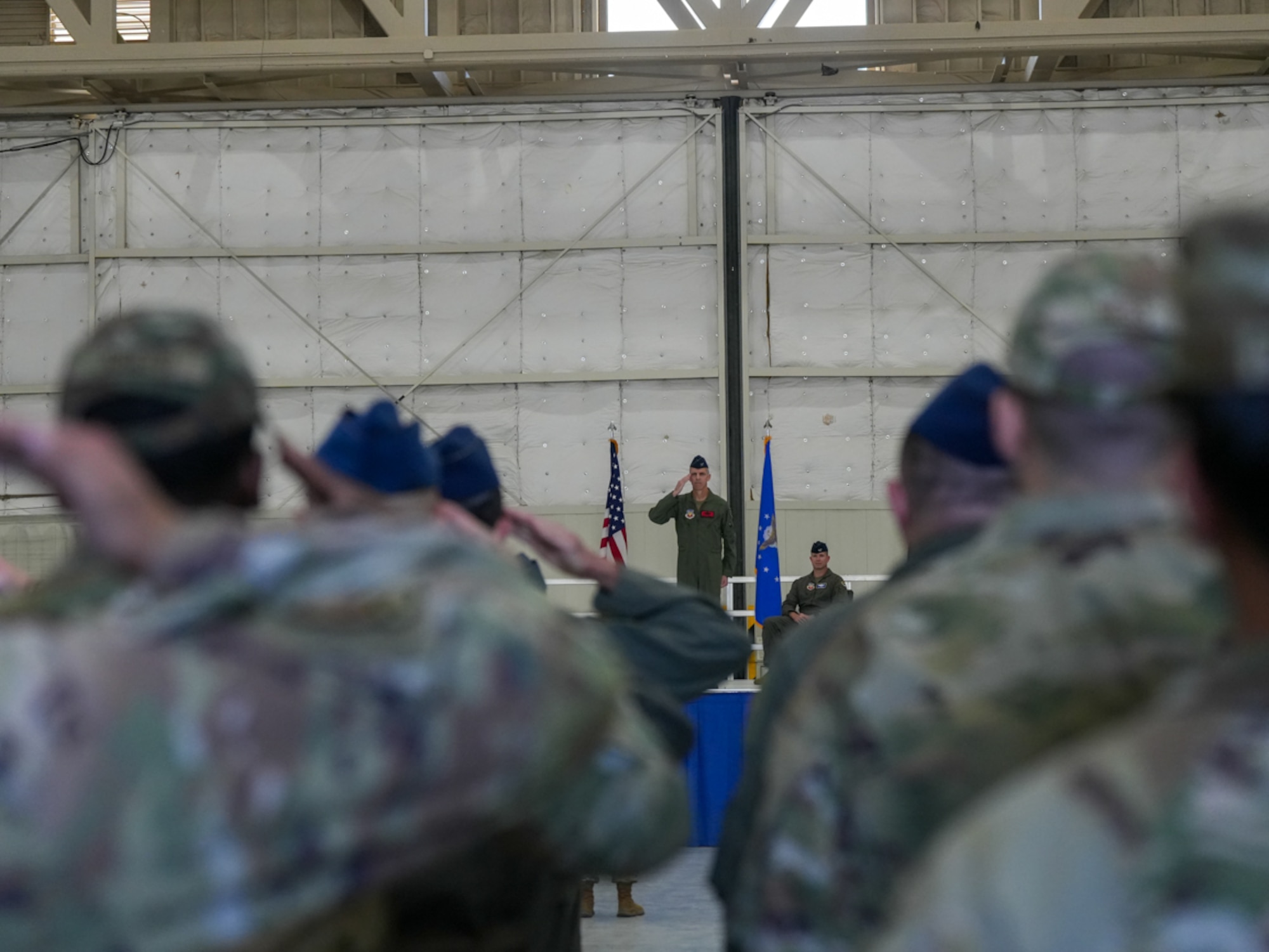 A man in a military uniform salutes military members.