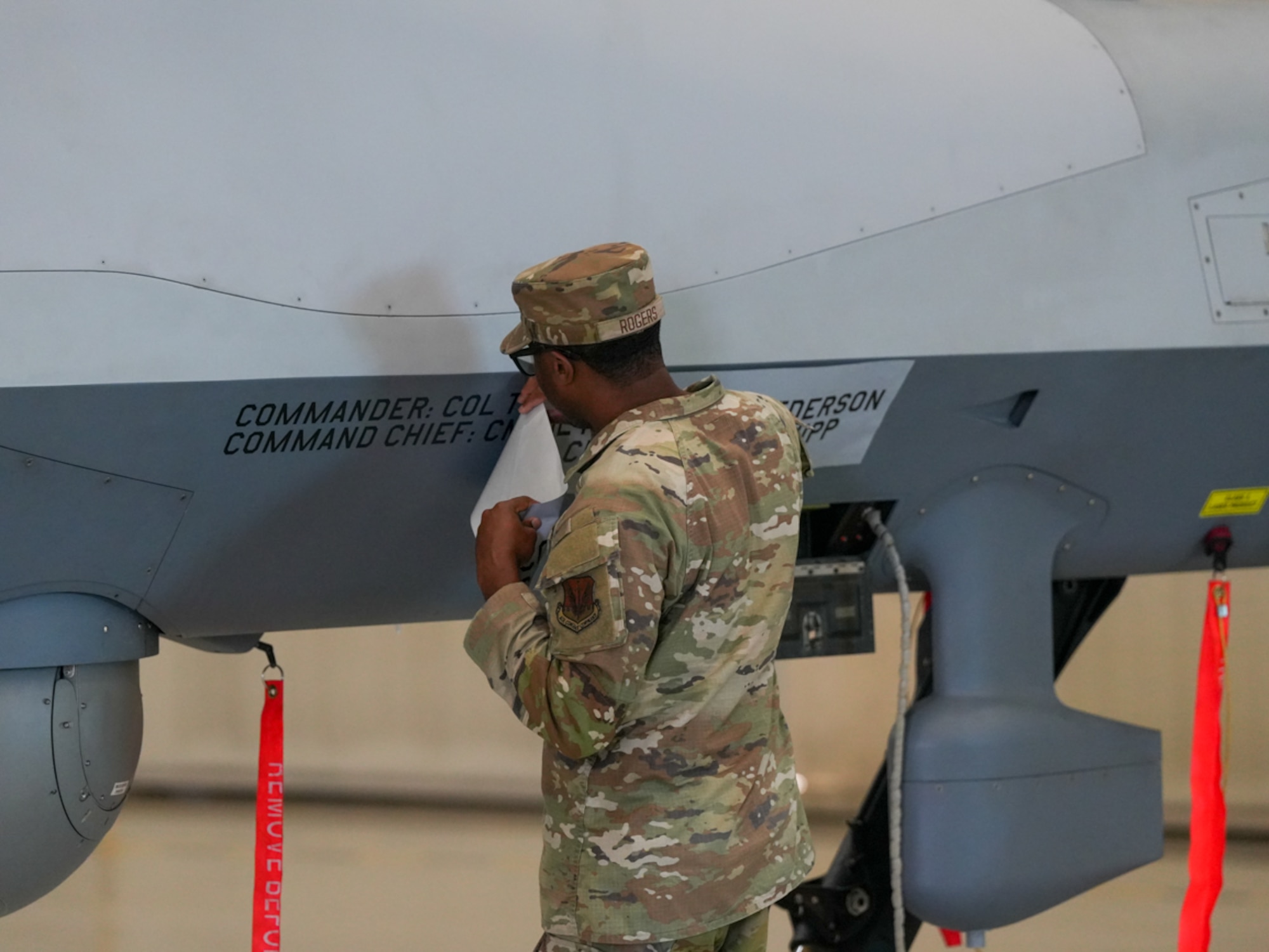 A man in a military uniform rips tape off of a remotely piloted aircraft.