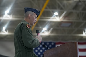 A man in a flight suit speaks into a microphone