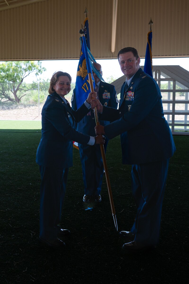 U.S. Air Force Col. Timothy Dalby, outgoing 17th Mission Support Group commander, passes the guidon to Col. Angelina Maguinness, 17th Training Wing commander, relinquishing command during the change of command ceremony at the 17th Security Forces Squadron kennels, Goodfellow Air Force Base, Texas, June 26, 2025. Passing the guidon represents the transfer of leadership responsibilities to the next commander. (U.S. Air Force photo by Airman 1st Class Brian Lummus)