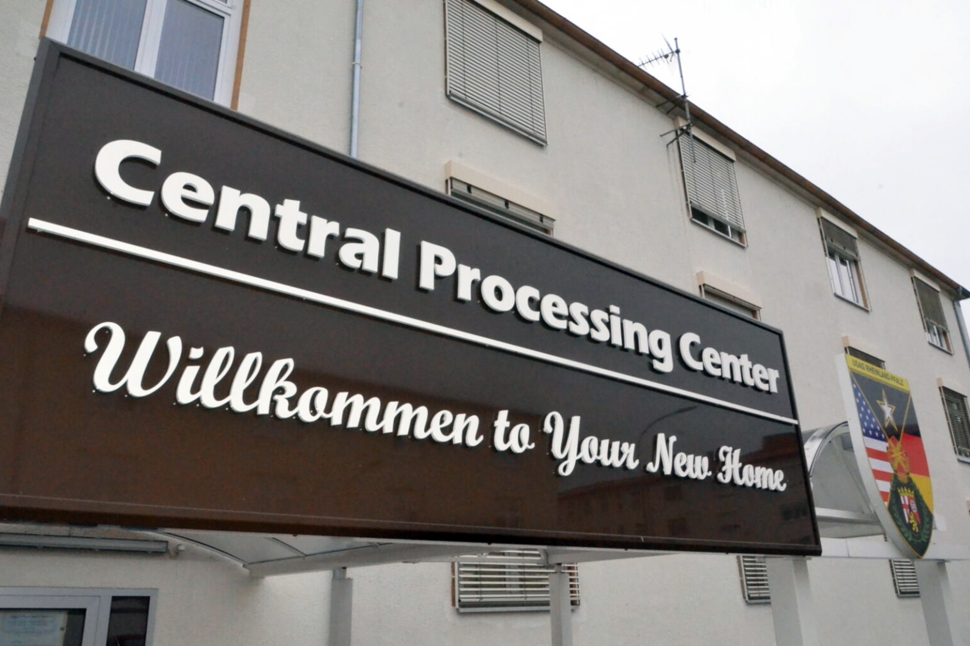 A sign on a building reads, "Central Processing Center Willkommen to Your New Home."
