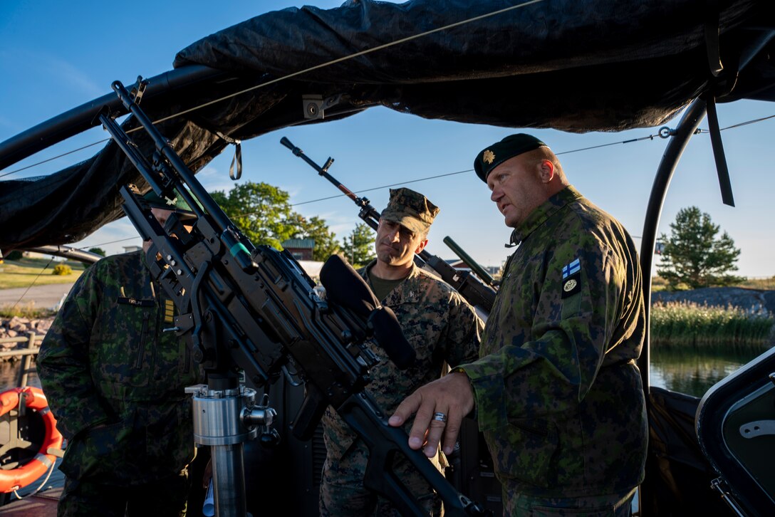 Finnish Lt. Senior Grade Leo Koponen, right, a combat boat platoon leader assigned to Nyland Brigade, showcases the capabilities of a U700 landing craft to U.S. Marine Corps Col. Paul Merida, center, commanding officer, 22nd Marine Expeditionary Unit (MEU), in Hanko, Finland, Aug. 10, 2022. The Kearsarge Amphibious Ready Group and 22nd MEU, under the command and control of Task Force 61/2, is on a scheduled deployment in the U.S. Naval Forces Europe area of operations, employed by U.S. Sixth Fleet to defend U.S., allied and partner interests. (U.S. Marine Corps photo by Staff Sgt. Brittney Vella)