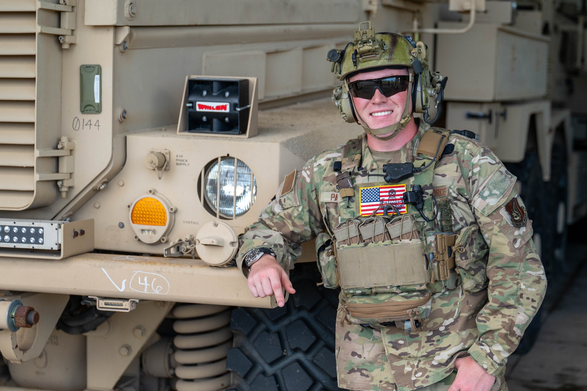 Service member poses for a photo in front of vehicle.
