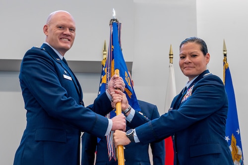 U.S. Air Force Col. Jens Lyndrup, 515th Air Mobility Operations Wing commander, left, presents the guidon to Col. Cataleya Carlson, 515th Air Mobility Operations Group incoming commander.