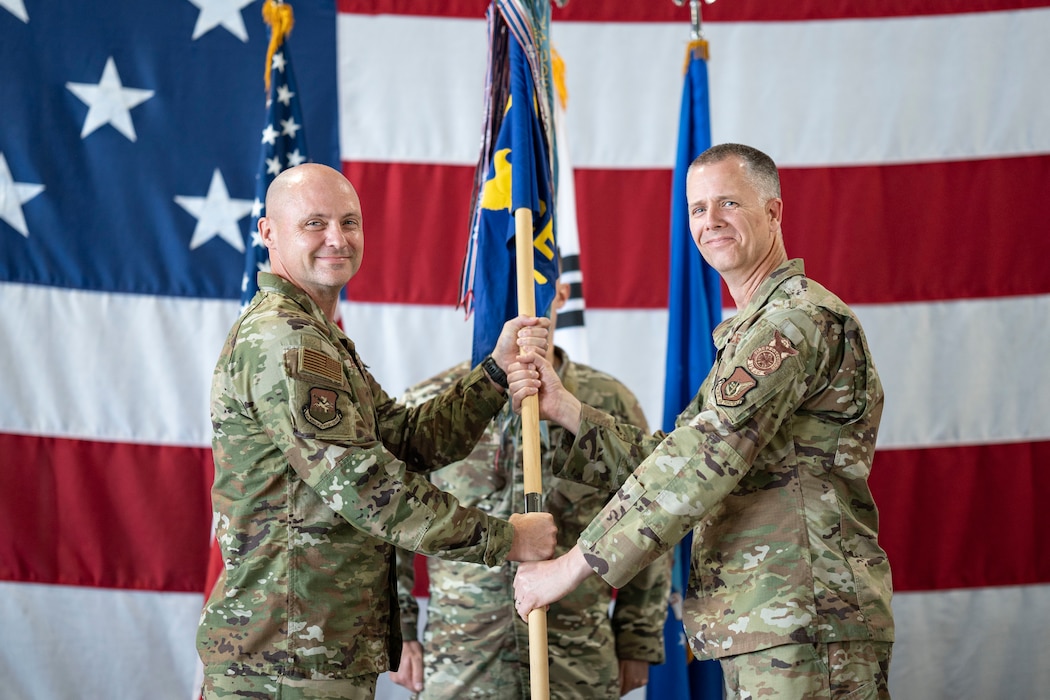 U.S. Air Force Col. Jeff Elliott, left, 51st Civil Engineering Group commander, passes  the guidon to Lt. Col. Kirk Hull, incoming 51st Civil Engineer Squadron commander, during a Change of Command ceremony at Osan Air Base, Republic of Korea, June 30, 2025.