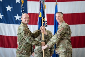 U.S. Air Force Col. Jeff Elliott, left, 51st Civil Engineering Group commander, passes  the guidon to Lt. Col. Kirk Hull, incoming 51st Civil Engineer Squadron commander, during a Change of Command ceremony at Osan Air Base, Republic of Korea, June 30, 2025.