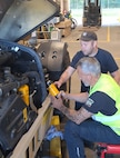 Michael Drutti, the automotive maintenance supervisor at the Zutendaal Army Prepositioned Stocks-2 worksite, watches a mechanic on his team install a new fuel filter on a Light Capability Rough Terrain Forklift at the Zutendaal APS-2 worksite, June 30, 2025. (U.S. Army courtesy photo)