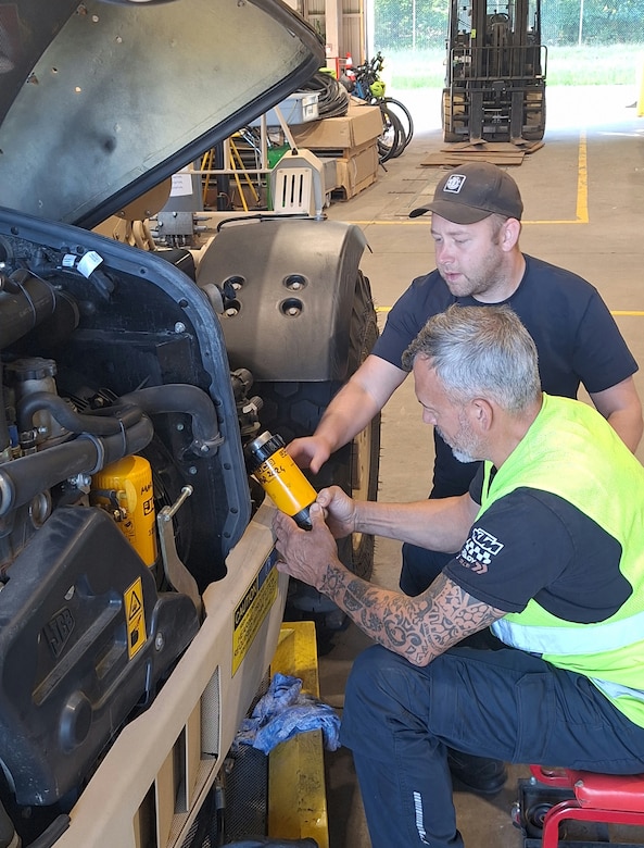 Michael Drutti, the automotive maintenance supervisor at the Zutendaal Army Prepositioned Stocks-2 worksite, watches a mechanic on his team install a new fuel filter on a Light Capability Rough Terrain Forklift at the Zutendaal APS-2 worksite, June 30, 2025. (U.S. Army courtesy photo)
