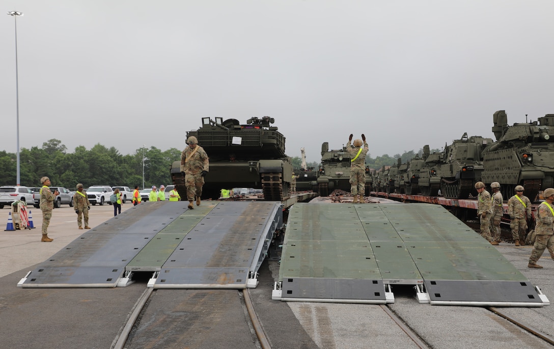 Soldiers direct two tanks off of a rail car using a RAIL system which provides a temporary ramp suitable for use by heavy equipment.