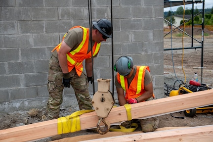 U.S. Army Staff Sgt. Zachary Williamson, left, and Spc. Pharez Telona, with the 176th Engineer Company, 420th Chemical Battalion, 96th Troop Command, Washington National Guard, prepares the beam for installation on the roof of a restroom facility at Charter Park, Orting, Wash, June 19, 2025.