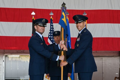 A presiding officer, left, passes the 52nd FW guidon to the incoming commander, during the 52nd FW change of command ceremony.