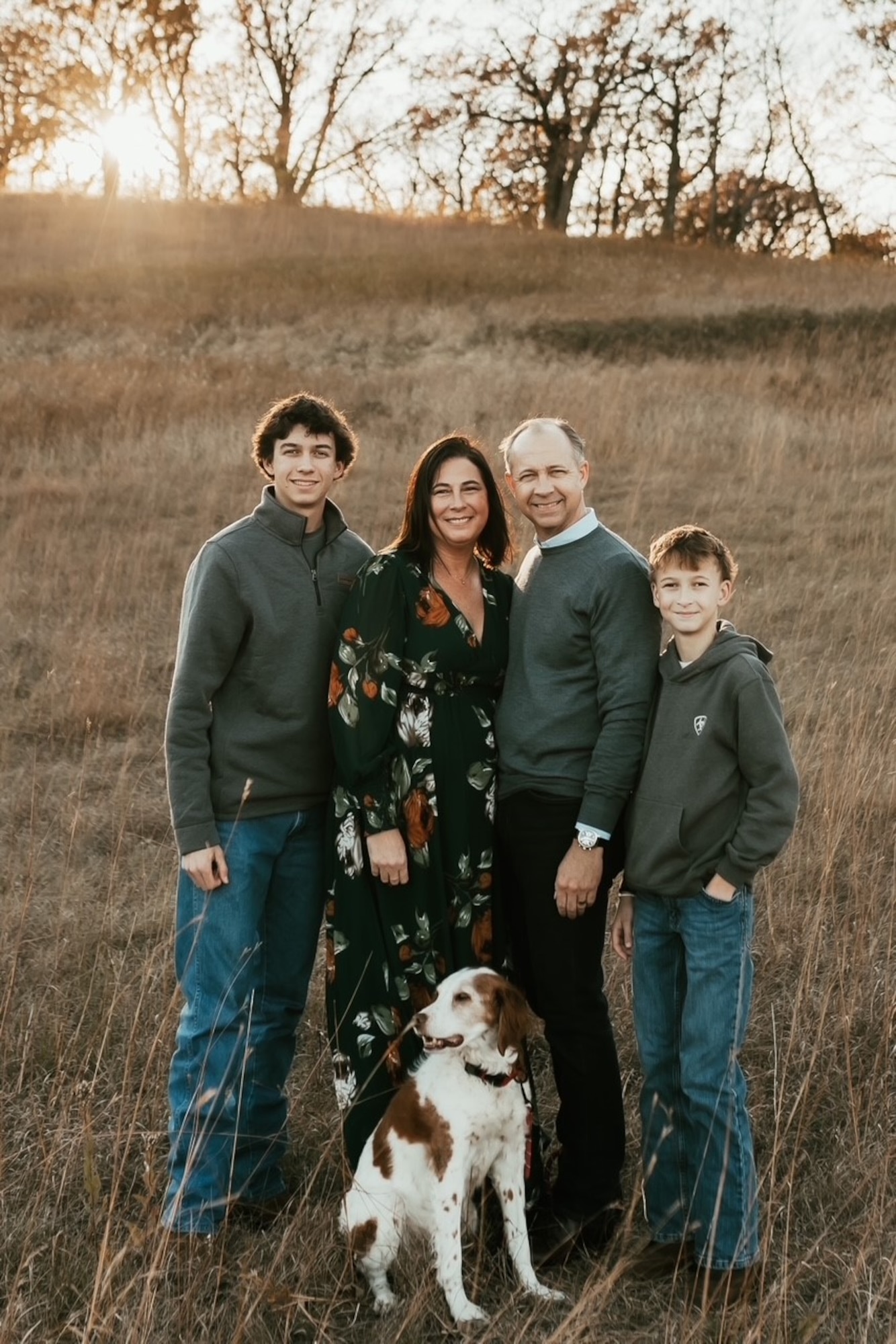 Family poses for photo with dog in wheat field.