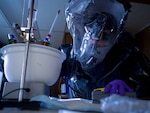 Virginia Air National Guard Tech. Sgt. Taylor Lincoln, 34th Civil Support Team, examines a simulated weapons of mass destruction chemical lab June 9, 2025, at AJ Dock, Juneau, Alaska, as part of Exercise ORCA 25. The exercise is a full-scale all-hazards chemical, biological, radiological, nuclear and high-yield explosives joint and interagency training exercise testing and evaluating the operational capability of the whole-of-government emergency management system.