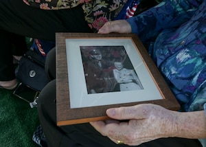 A photo of a couple is held in the lap of a woman.