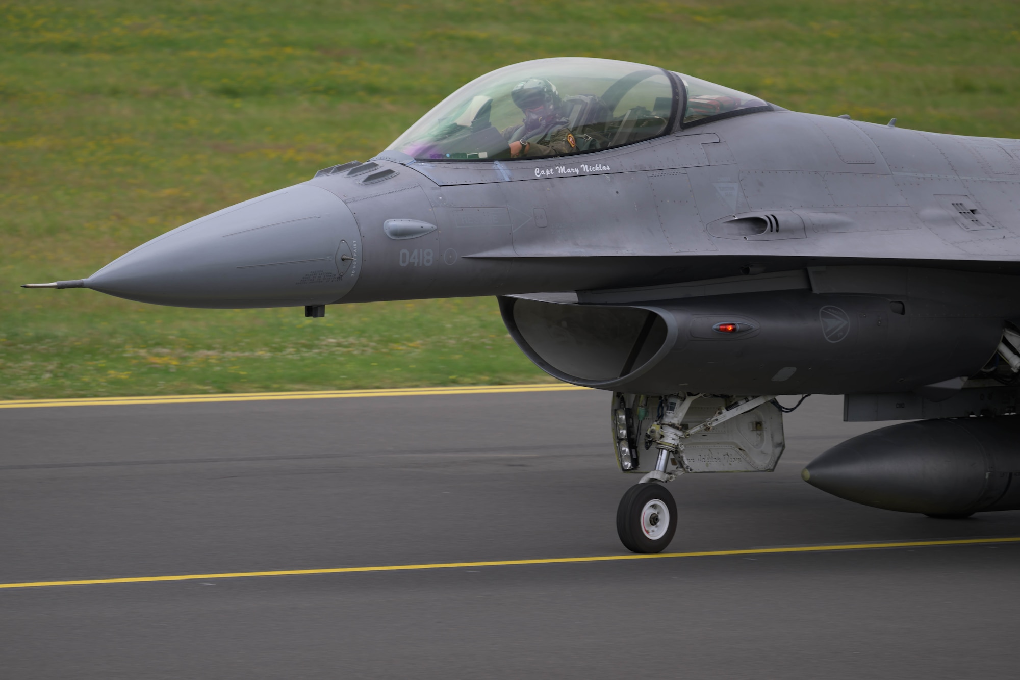 An F-16 fighter aircraft taxis along the flightline.