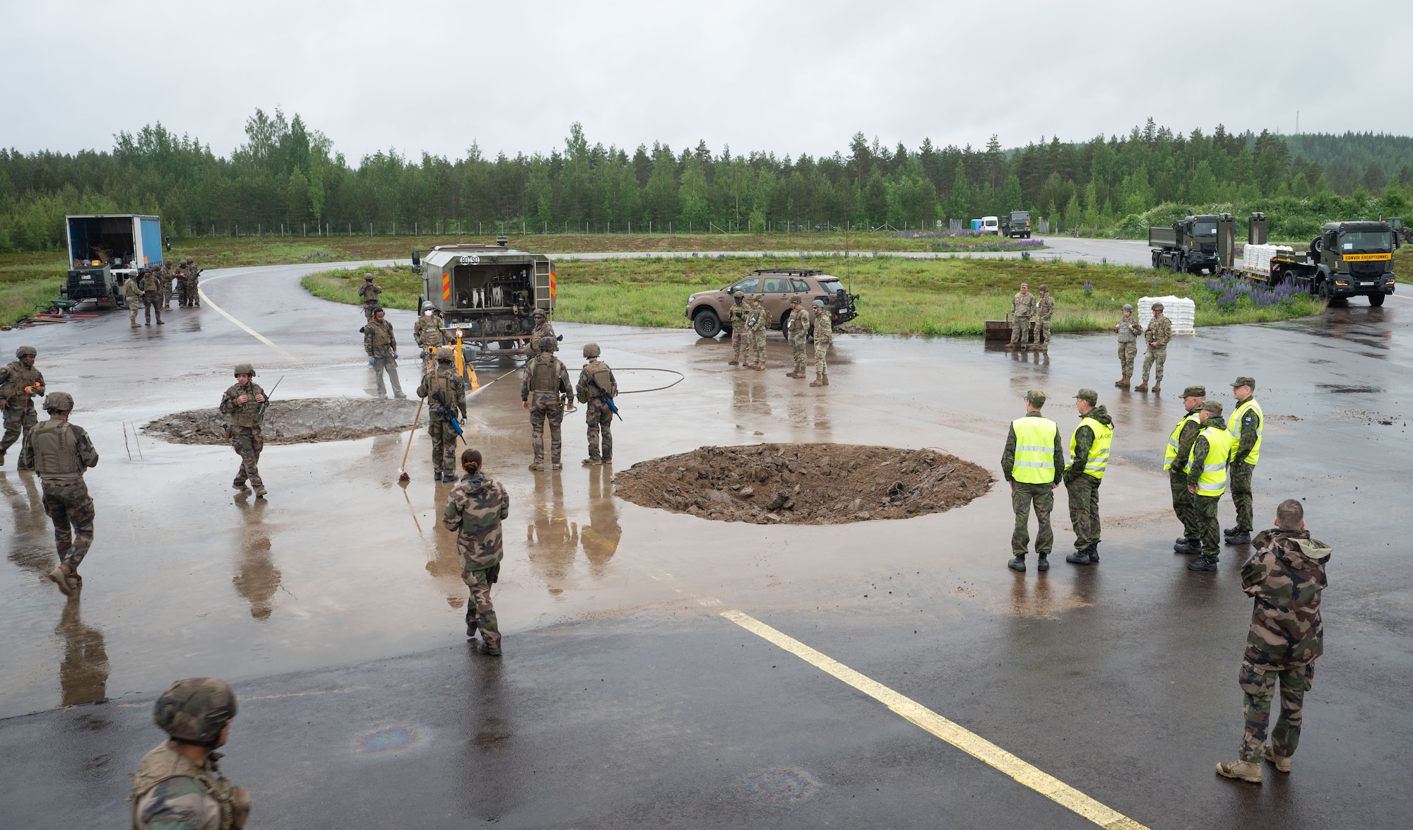 U.S., U.K., French, and Finnish Air Force members repair a damaged airfield during exercise Atlantic Trident 25 at Halli Air Base, Finland, June 18, 2025. AT25 joint training and strategic warfighting exercises further Allied quick response and Agile Combat Employment to the eastern flank. This exercise utilized training craters for rapid excavating, clearing and quick concrete filling required in a joint operating environment. (U.S. Air Force photo by Senior Airman Ashley Talley)