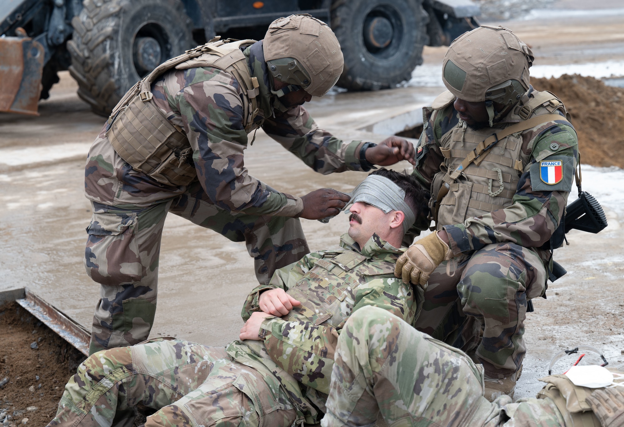 U.S. Air Force Airmen and French Air and Space Force members initiate tactical combat casualty care amid airfield damage repairs during exercise Atlantic Trident 25 at Halli Air Base, Finland, June 18, 2025. A simulated explosive incident during airfield damage repair training demonstrated seamless Allied integration throughout contested environments. Atlantic Trident 25 is part of a broader effort to rebuild U.S. warfighting capabilities, restore the warrior mindset and re-establish credible deterrence in a contested environment. (U.S. Air Force photo by Senior Airman Ashley Talley)