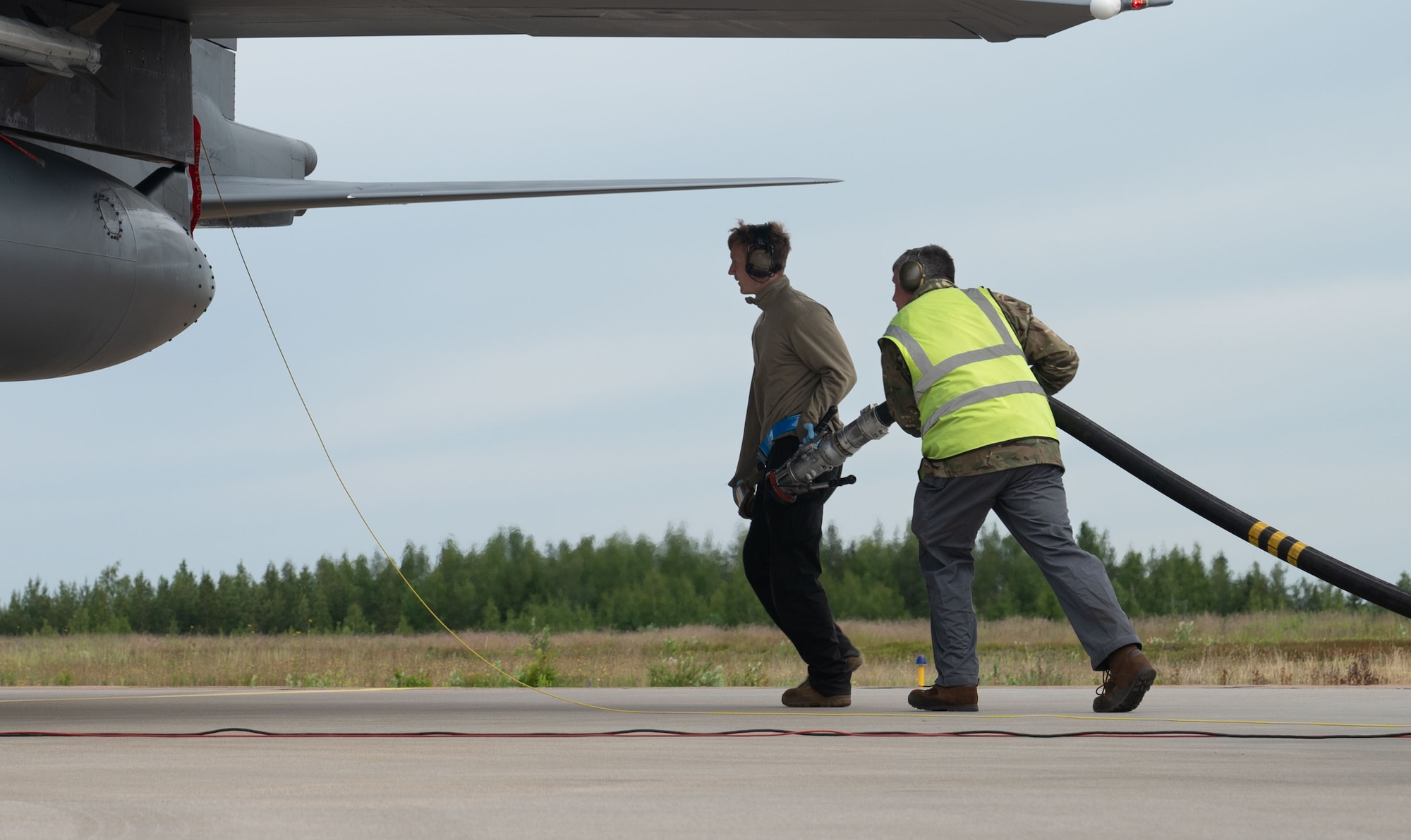 A U.S. Airman prepares to refuel a U.S. Air Force F-15E Strike Eagle during hot pit refueling with a Royal Air Force member at exercise Atlantic Trident 25 at Halli Air Base, Finland, June 23, 2025. Recurring training events like Atlantic Trident allow the U.S. to forward deploy combat power, train in complex air environments and sharpen integration with close partners. (U.S. Air Force photo by Senior Airman AshleyTalley)