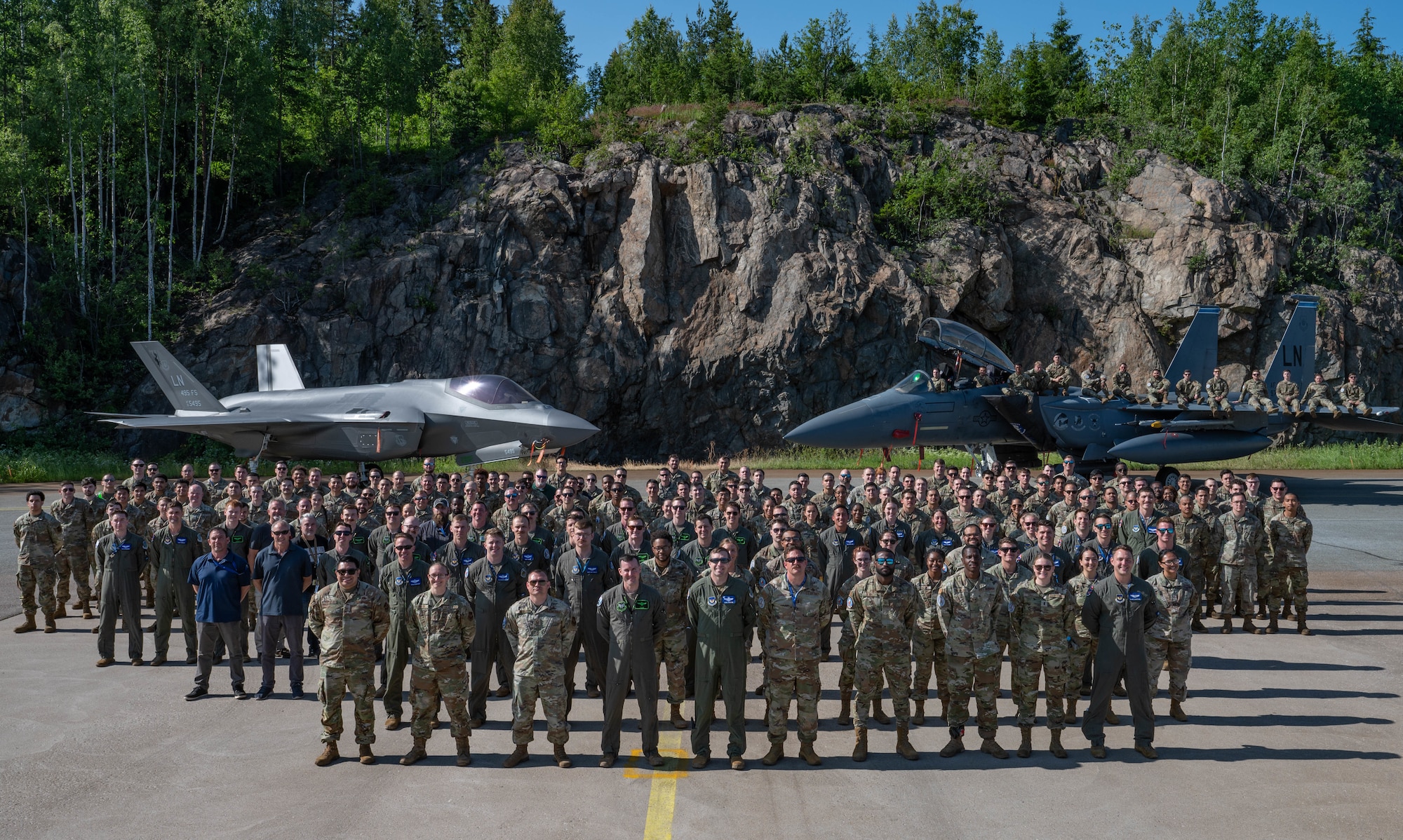 U.S. Airmen, assigned to the 48th Fighter Wing, pose for a photo in front of a U.S. Air Force F-15E Strike Eagle and F-35A Lightning II during exercise Atlantic Trident 25 at Pirkkala Air Base, Finland, June 26, 2025. AT 25 is a tactical-level field training exercise hosted by the Finnish Air Force, focused on improving interoperability and integration between fourth- and fifth-generation fighter aircraft. (U.S. Air Force photo by Airman 1st Class Sierra Casteel)