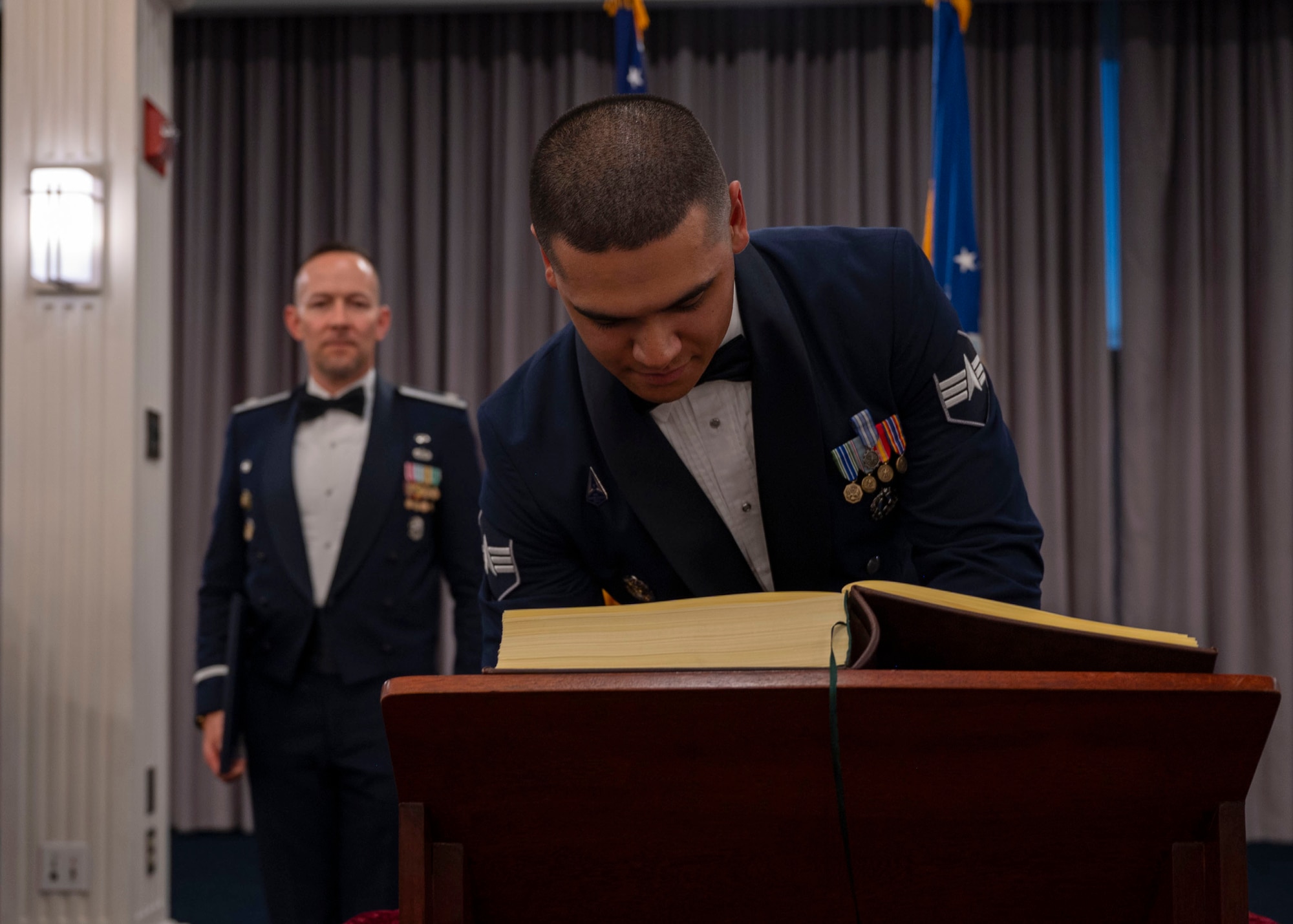 photo of an Air Force Honor Guard member signing his name in a book that is placed on a podium