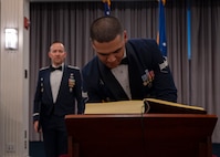photo of an Air Force Honor Guard member signing his name in a book that is placed on a podium