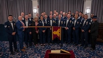 group photo of former and current Air Force Honor Guard members while one holds a guidon horizontally across the group