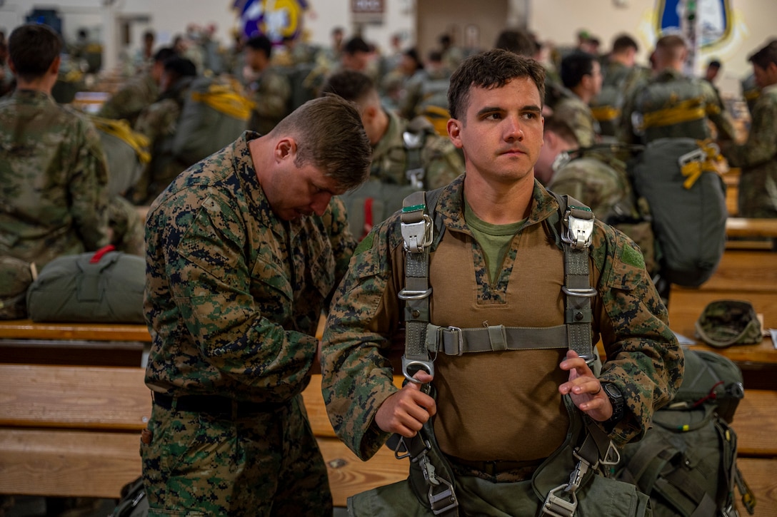 U.S. Marine Corps Sgt. Nicholas Noel, left, 4th Air Naval Gunfire Liaison Company field artillery fire control Marine, inspects the parachute of Staff Sgt. Lucas Cook, 4th ANGLICO transmission chief, before a static line jump from a C-130 Hercules during Red Flag-Alaska 25-2 at Joint Base Elmendorf-Richardson, Alaska, June 25, 2025. This exercise simulates the complexities of potential Indo-Pacific scenarios, providing unique opportunities to integrate various forces into joint, coalition and multilateral training from simulated forward operating bases, enhancing the U.S. and allies’ ability to respond effectively to contingencies in the region. (U.S. Air Force photo by Senior Airman Matthew Arachikavitz)
