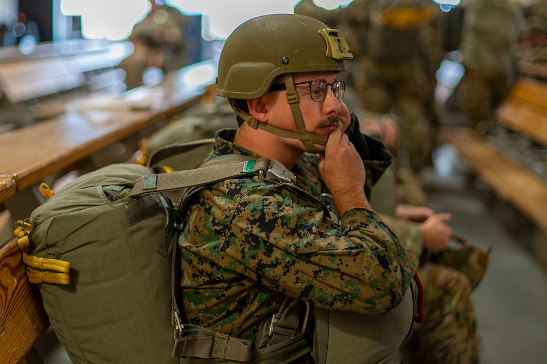 U.S. Marine Corps Cpl. Robert Furton, 4th Air Naval Gunfire Liaison Company joint fires observer, secures his helmet before a static line jump from a C-130 Hercules during Red Flag-Alaska 25-2 at Joint Base Elmendorf-Richardson, Alaska, June 25, 2025. This exercise simulates the complexities of potential Indo-Pacific scenarios, providing unique opportunities to integrate various forces into joint, coalition and multilateral training from simulated forward operating bases, enhancing the U.S. and allies’ ability to respond effectively to contingencies in the region. (U.S. Air Force photo by Senior Airman Matthew Arachikavitz)
