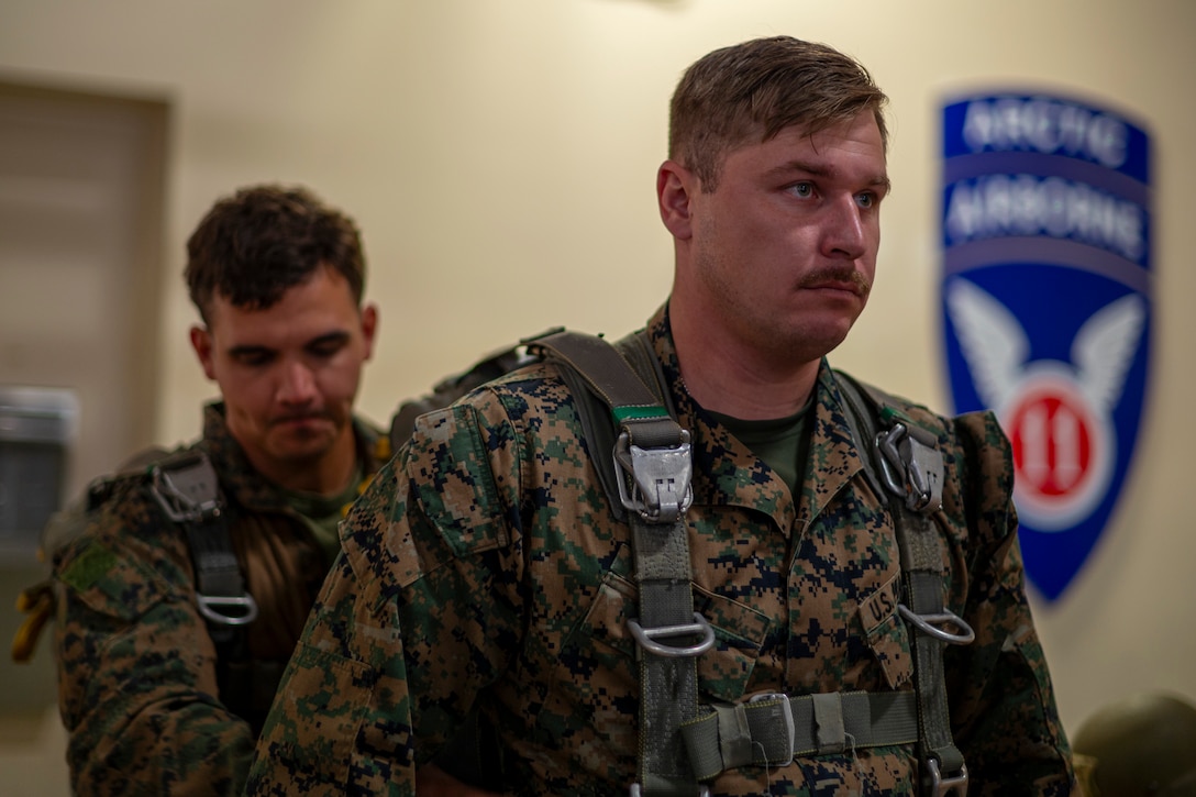 U.S. Marine Corps Staff Sgt. Lucas Cook, left, 4th Air Naval Gunfire Liaison Company transmission chief, inspects the parachute of Sgt. Nicholas Noel, 4th ANGLICO field artillery fire control Marine, before a static line jump from a C-130 Hercules during Red Flag-Alaska 25-2 at Joint Base Elmendorf-Richardson, Alaska, June 25, 2025. This exercise simulates the complexities of potential Indo-Pacific scenarios, providing unique opportunities to integrate various forces into joint, coalition and multilateral training from simulated forward operating bases, enhancing the U.S. and allies’ ability to respond effectively to contingencies in the region. (U.S. Air Force photo by Senior Airman Matthew Arachikavitz)