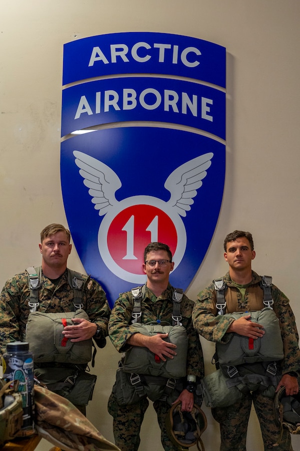 U.S. Marine Corps Sgt. Nicholas Noel, left, field artillery fire control Marine, Cpl. Robert Furton, center, joint fires observer and Staff Sgt. Lucas Cook, transmission chief, all assigned to the 4th Air Naval Gunfire Liaison Company, wait to board a C-130 Hercules for a static line jump during Red Flag-Alaska 25-2 at Joint Base Elmendorf-Richardson, Alaska, June 25, 2025. This exercise simulates the complexities of potential Indo-Pacific scenarios, providing unique opportunities to integrate various forces into joint, coalition and multilateral training from simulated forward operating bases, enhancing the U.S. and allies’ ability to respond effectively to contingencies in the region. (U.S. Air Force photo by Senior Airman Matthew Arachikavitz)