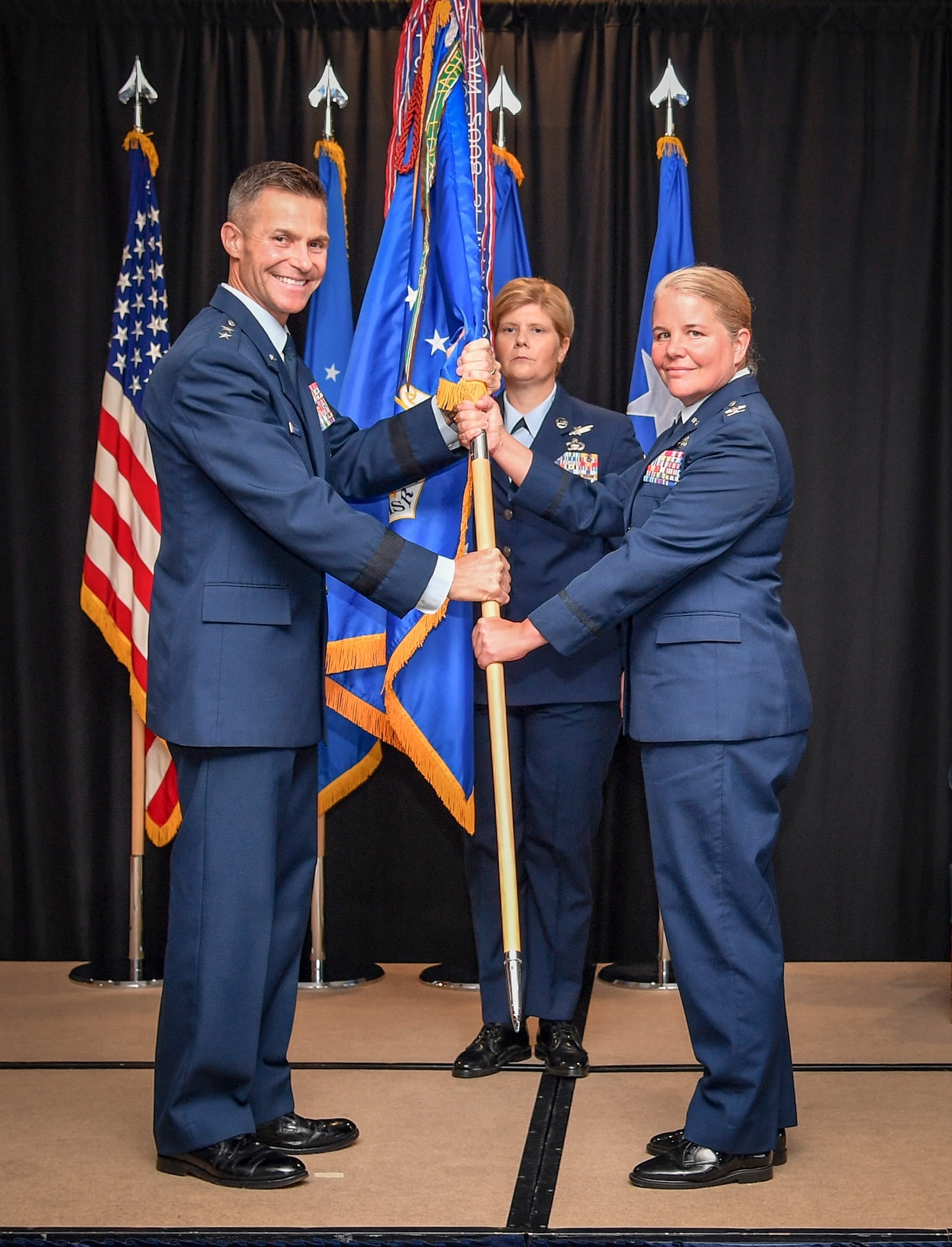 Two Air Force members hold onto a unit guidon/flag.