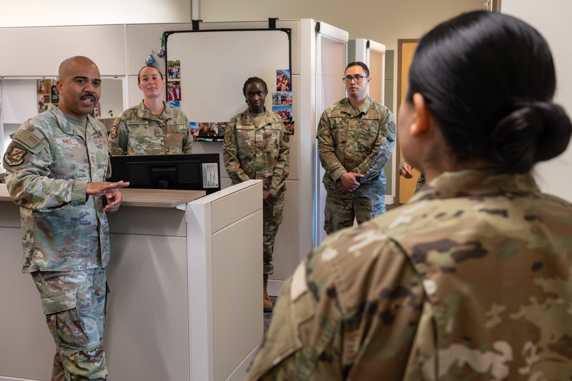 An individual in military uniform speaks to a small group.
