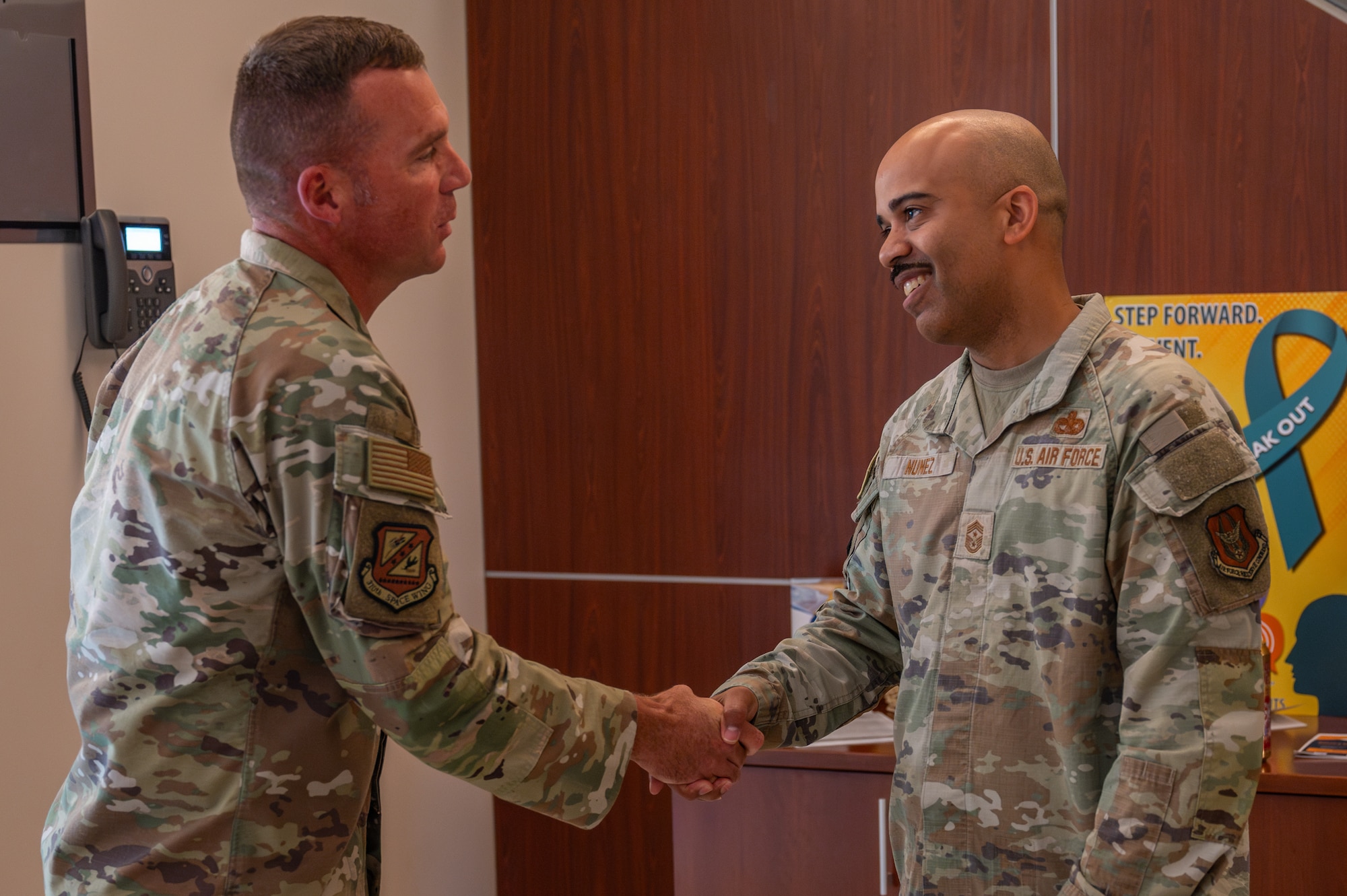 Two individuals in military uniform shake hands.