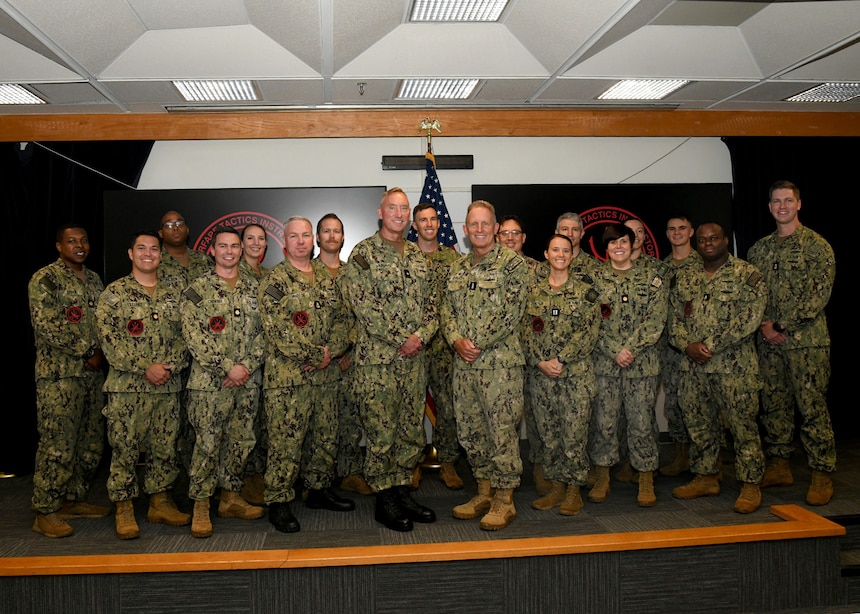 Rear Adm. Brian Harding, Commander, Naval Information Warfighting Development Center and Vice Adm. Mike Vernazza, Commander, Naval Information Forces, pose with the 17 new Information Warfare (IW) Warfare Tactics Instructors (WTIs). The graduation marks a significant milestone, bringing the total number of IW WTIs in the cadre to 300. (U.S. Navy Photo by Robert Fluegel/RELEASED)