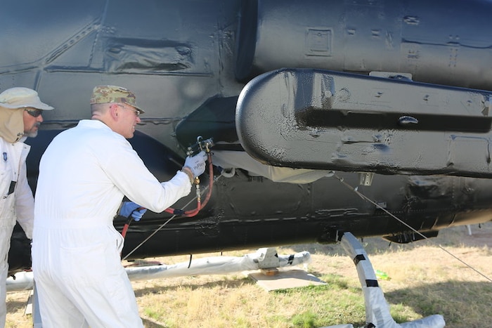 Gen. Richardson sprays a protective vinyl compound on a helicopter.