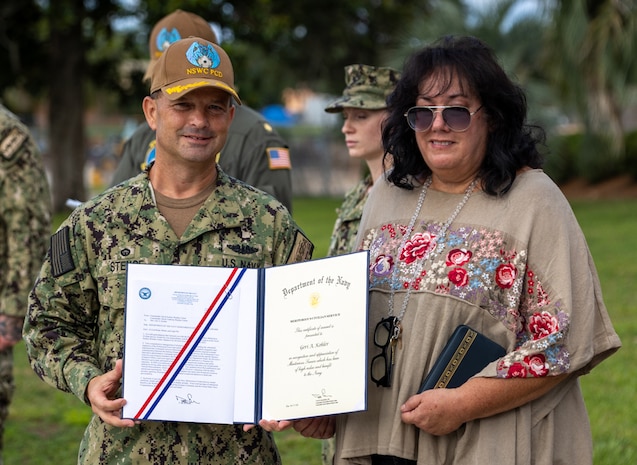 Naval Surface Warfare Center Panama City Division Commanding Officer Capt. Paul Stence, Jr., awards Geri Kohler, NSWC PCD military liaison, with the Department of the Navy Meritorious Civilian Service Award, June 13. Kohler manages all active-duty personnel and their administrative functions warfighters to seamlessly mesh and support the mission here while ensuring their operational readiness. (U.S. Navy photo by Bob Lindee)