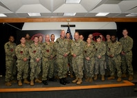 Rear Adm. Brian Harding, Commander, Naval Information Warfighting Development Center and Vice Adm. Mike Vernazza, Commander, Naval Information Forces, pose with the 17 new Information Warfare (IW) Warfare Tactics Instructors (WTIs). The graduation marks a significant milestone, bringing the total number of IW WTIs in the cadre to 300. (U.S. Navy Photo by Robert Fluegel/RELEASED)