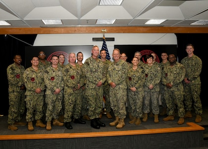 Rear Adm. Brian Harding, Commander, Naval Information Warfighting Development Center and Vice Adm. Mike Vernazza, Commander, Naval Information Forces, pose with the 17 new Information Warfare (IW) Warfare Tactics Instructors (WTIs). The graduation marks a significant milestone, bringing the total number of IW WTIs in the cadre to 300. (U.S. Navy Photo by Robert Fluegel/RELEASED)