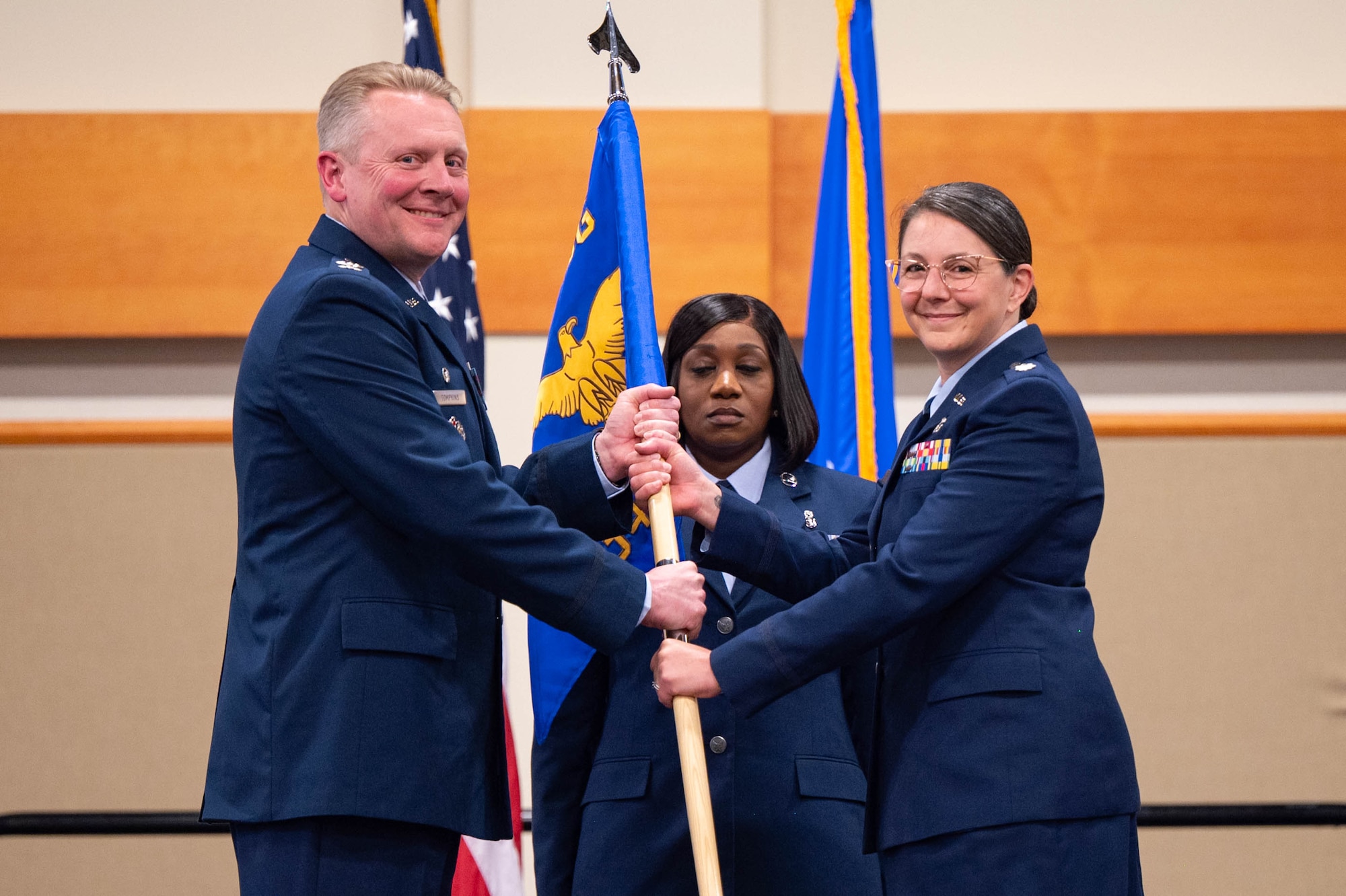 Uniformed personnel hold a flag.