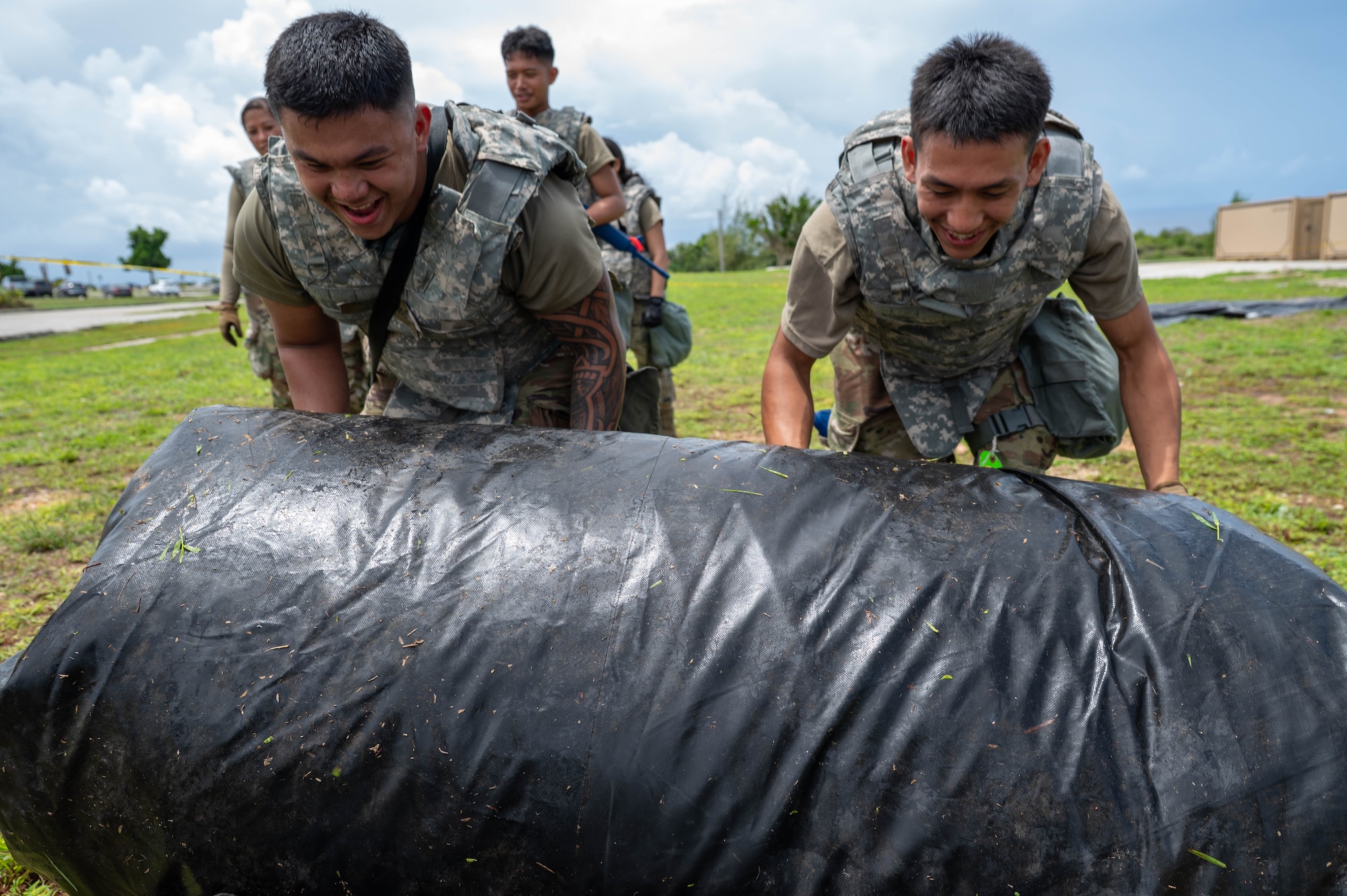 Senior Airman Ely Pocaigue and Senior Airman Josie Cruz, both from the 44th Aerial Port Squadron, roll up a tent tarp during Exercise Pacific Warrior 2025 at Andersen Air Force Base, Guam, June 6, 2025.