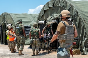 U.S. Air Force Citizen Airmen of the 624th Aeromedical Staging Squadron transport a simulated injured patient into an Expeditionary Medical Support tent during Exercise Pacific Warrior 2025 at Joint Base Pearl Harbor Hickam, Hawaii, June 6, 2025.