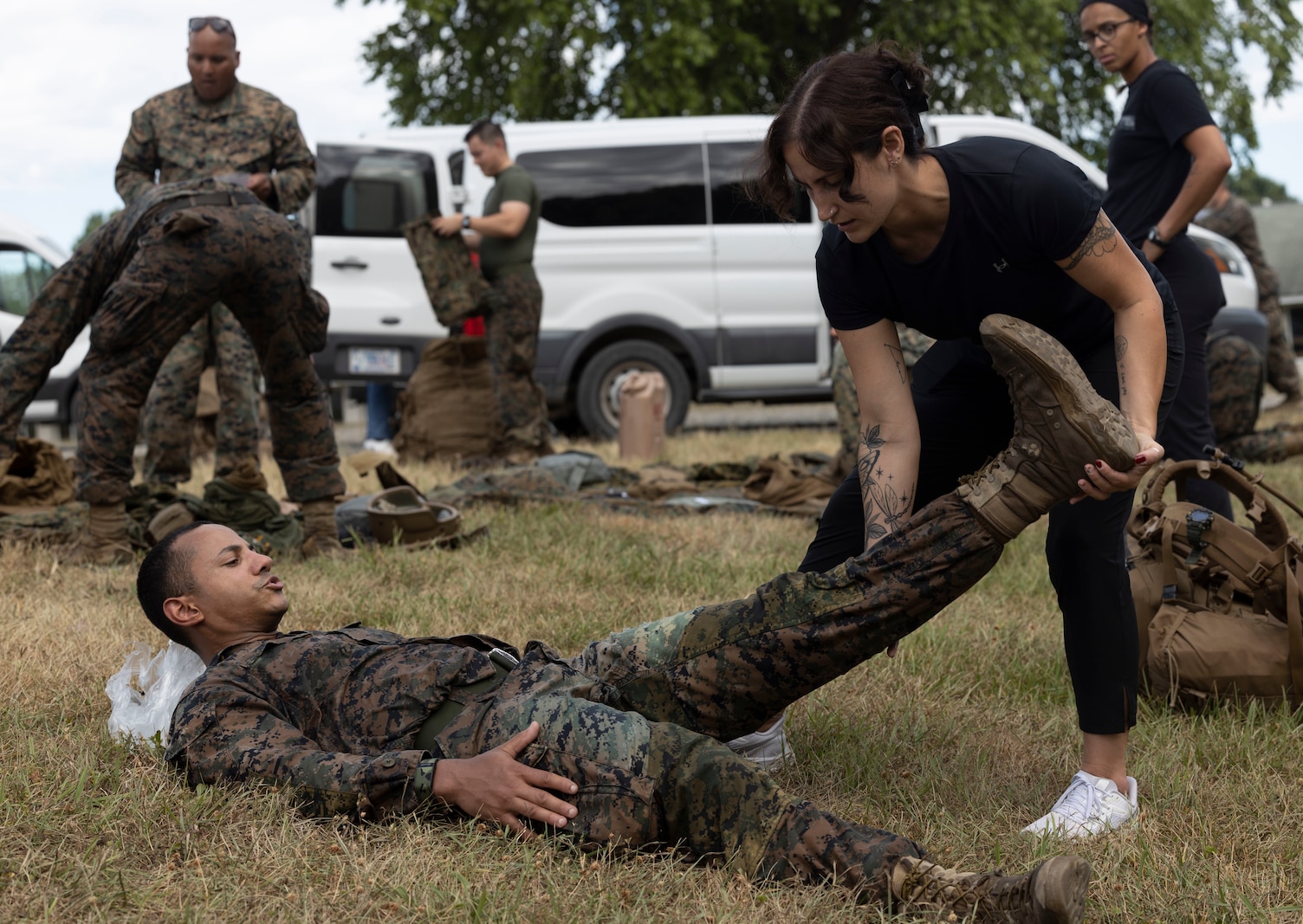 Athletic trainer stretches the leg of a Marine while he lays on his back after a hike.